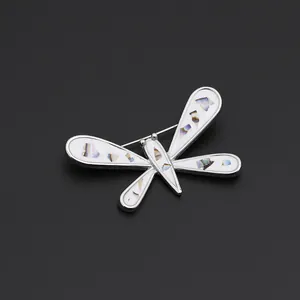 Macro shot of a silver dragonfly brooch with iridescent shell wings on black background