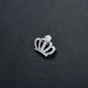 Détail de la broche couronne en argent avec zircons brillants sur fond de cuir noir