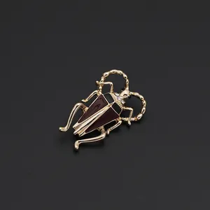 Detailed macro view of a vintage golden beetle brooch with deep red enamel wings and rhinestones