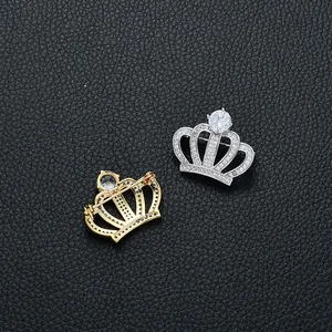 Détail de broches en forme de couronne dorée et argentée avec zircon sur cuir noir