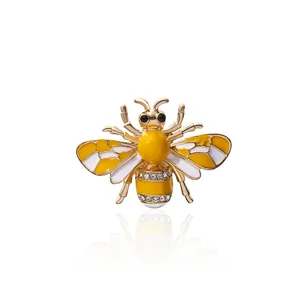 Golden honey bee brooch with yellow enamel and sparkling rhinestones on white background