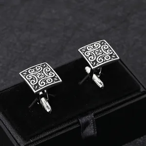 Vintage square silver cufflinks with intricate floral patterns in black jewelry box