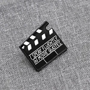 Dettaglio della spilla a ciak con testo I Speak Fluently in Movie Quotes su tessuto
