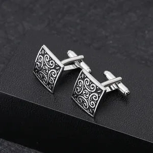 Macro view of square cufflinks featuring intricate black vintage floral patterns
