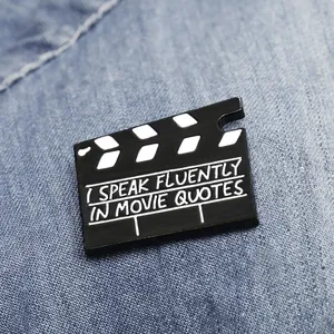 Spilla smaltata vintage a ciak cinematografico con scritta 'I SPEAK FLUENTLY IN MOVIE QUOTES'