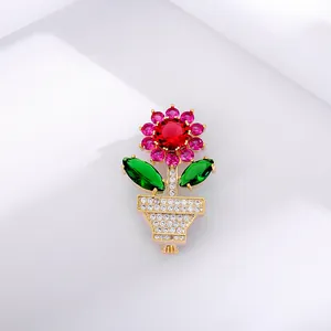 Macro shot of sunflower flowerpot brooch with red pink crystals and gold plating