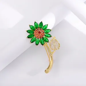 Macro detail of sunflower brooch featuring green gems and red crystals on golden stem