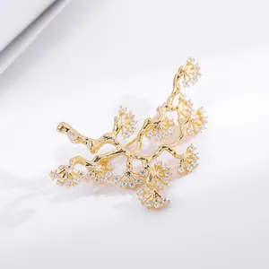 Macro shot of gold branch brooch featuring intricate pine tree design with white zircons