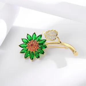 Macro shot of sunflower brooch with green petals and red center on white background