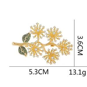 Elegant gold pine branch brooch with white and green crystals in a minimalist design