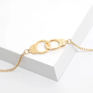Macro shot of gold handcuff bracelet with FREEDOM engraving on white geometric background