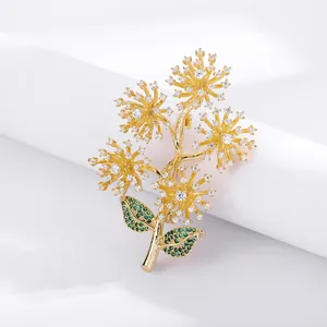 Detailed view of a gold pine branch brooch with sparkling white clusters and green leaves