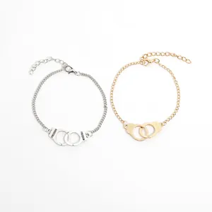 Detail of interlocking handcuffs bracelet with FREEDOM engraving in gold and silver