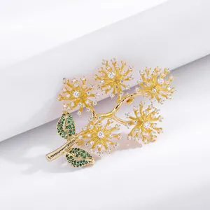 Detail of gold pine branch brooch with green leaves and sparkling white crystals