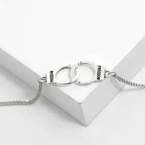 Detailed close-up of silver handcuff charm bracelet featuring Freedom engraving