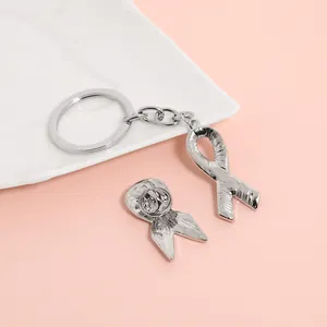 Detail of pink ribbon alloy brooch and keychain set with polished silver finish