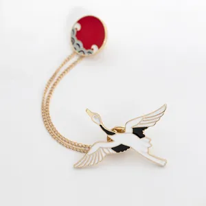 Detail of enameled crane brooch with red sun badge and golden hanging chains
