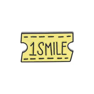 Yellow enamel plane ticket brooch with 1 SMILE engraving on a white background