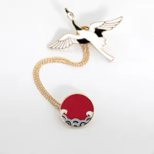 Detail of Japanese style crane brooch with wave badge and delicate golden connecting chain
