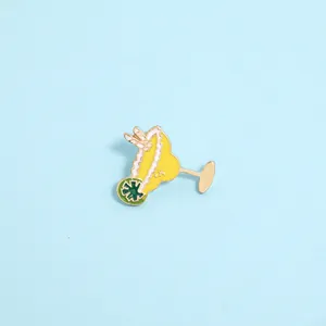 Detail of vibrant yellow lemon cocktail enamel pin with green lime slice on blue background