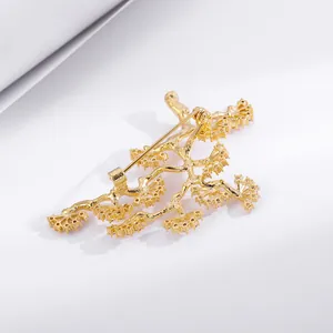 Macro view of golden pine branch brooch showing the intricate back pin and metal texture