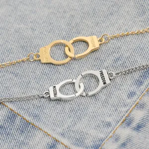 Gold and silver handcuff bracelets engraved with FREEDOM on denim background