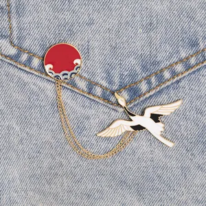 Japanese style crane enamel brooch with sun and wave badges on blue denim background