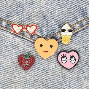 Set of five creative colorful enamel pins including heart and ice cream icons on denim