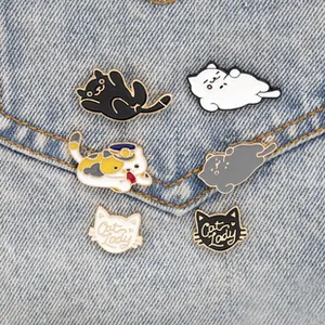 Detail of cute cat enamel pins and Cat Lady badges pinned on light blue denim fabric