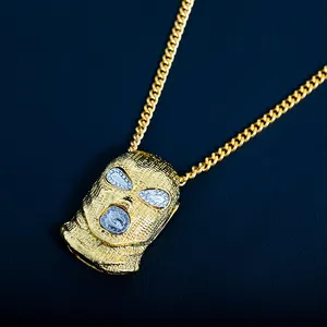 Détail macro du pendentif cagoule dorée avec cristaux et chaîne gourmette sur cuir