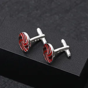 Detailed view of silver-toned round cufflinks with red spiral enamel on a black jewelry box