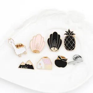 Cartoon enamel pin set with alpaca and house designs on a white ceramic tray