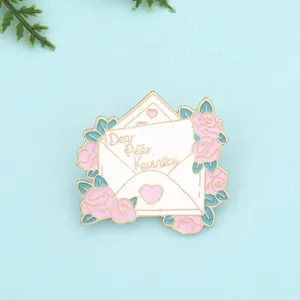 Macro detail of enamel envelope brooch featuring pink roses and Dear Peter Kavinsky text