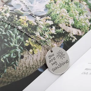 Détail macro du pendentif rond argenté avec You Are My Sunshine et une icône de soleil