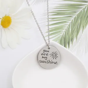 Vue détaillée du collier avec pendentif soleil gravé sur un plateau blanc