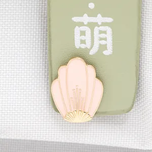 Macro shot of pink enamel cherry blossom petal pin with elegant gold metal edging details