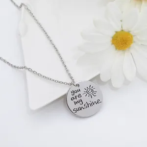 Détail macro du pendentif soleil argenté gravé You are my sunshine pour couples