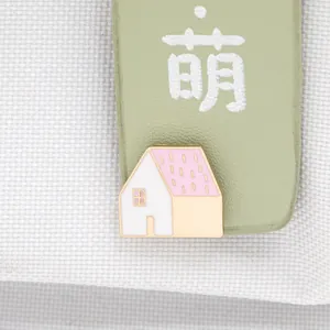 Close-up of a cozy house-shaped enamel brooch with pink dots on white metal