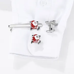 Dettaglio dei gemelli di Babbo Natale e fermacravatta su un polsino di camicia bianca