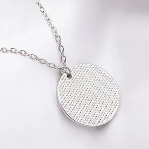 Détail du collier soleil argenté avec texture granuleuse sur fond de satin blanc