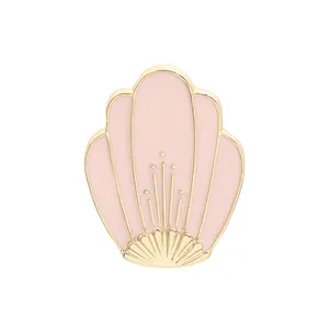 Detail view of pink enamel shell brooch with gold metallic edges and dotted patterns