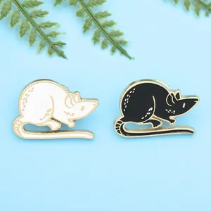 Close-up of cute black and white enamel mouse badges with gold-toned metal detailing