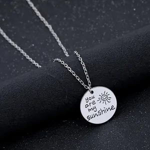 Collier avec pendentif rond argenté gravé soleil sur un présentoir noir élégant