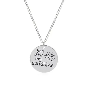 Collier minimaliste argenté avec pendentif soleil et gravure You are my sunshine sur fond blanc