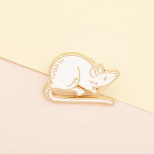 Detail of white enamel mouse brooch with gold metal trim and cute spotted tail texture