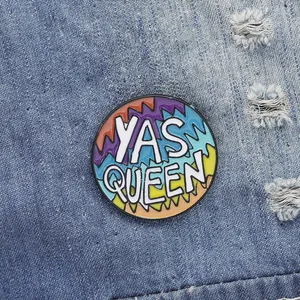 Macro shot of YAS QUEEN enamel pin with rainbow stripes on blue denim jacket fabric