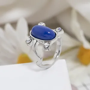 Dettaglio anello con zaffiro blu ovale e cristalli scintillanti su fascia argento