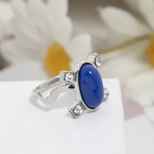 Dettaglio di un anello con gemma blu ovale, zirconi bianchi e fascia d'argento ondulata