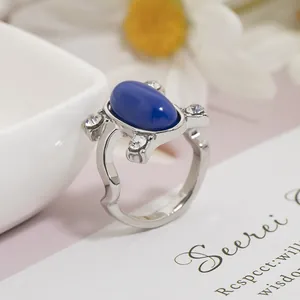 Dettaglio macro di anello d'argento con pietra blu ovale e quattro accenti in zircone