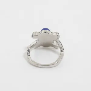 Dettaglio di un anello d'argento con pietra blu ovale e fascia con design a onde